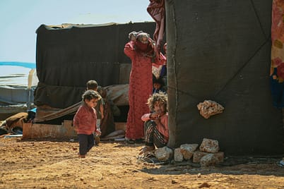 pexels-photo-11617826-11617826 Children playing outside a tent in a Syrian refugee camp, highlighting social issues.