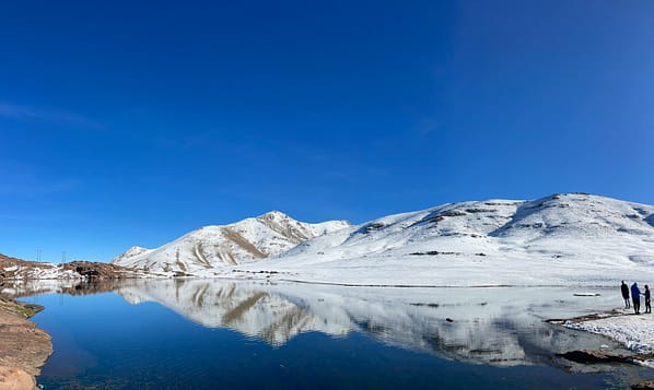 pexels-photo-30076089-30076089 Serene winter scene in Oukaimeden, Morocco with snowy mountains and a clear lake reflection.